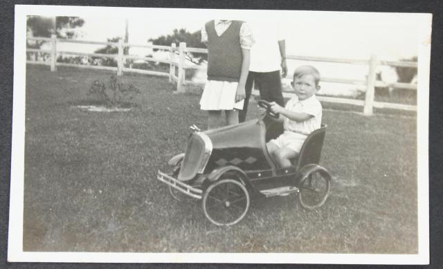 John Anton-Smith in pedal car on lawn by HKEC staff quarters