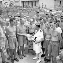 Cmdr. Peter MacRitchie of HMCS Prince Robert with liberated Canadian prisoners of war at Sham Shui Po Camp, Hong Kong 