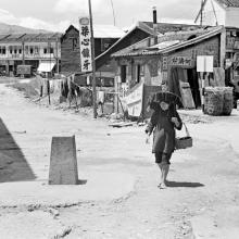 Woman walking through Shau Tau Kok village past border marker