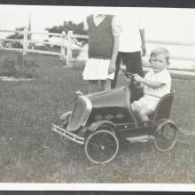 John Anton-Smith in pedal car on lawn by HKEC staff quarters