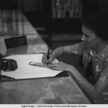 Hong Kong, an American evacuee signing a Travelers cheque during World War II