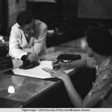 Hong Kong, American evacuee writing a travelers cheque during World War II